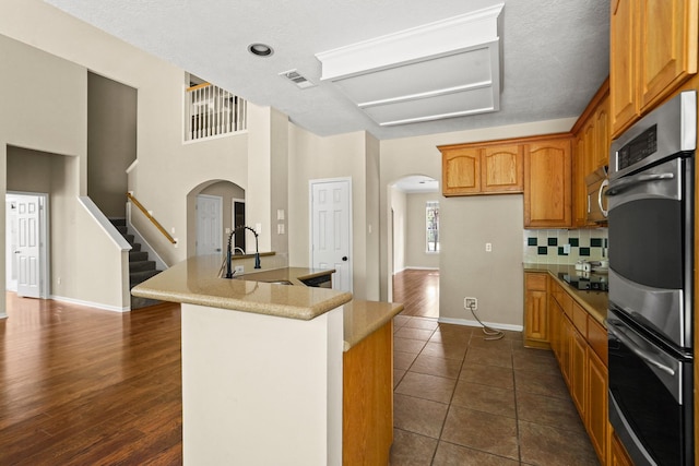 kitchen featuring backsplash, a textured ceiling, stainless steel appliances, dark wood-type flooring, and sink