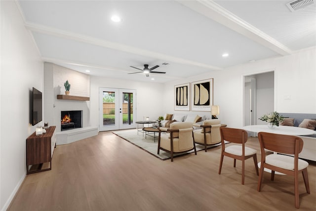 living room with beamed ceiling, light hardwood / wood-style floors, ceiling fan, and a fireplace