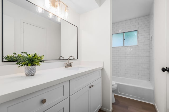 full bathroom featuring tiled shower / bath, hardwood / wood-style floors, vanity, and toilet