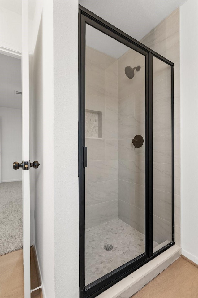 bathroom featuring wood-type flooring and a shower with shower door