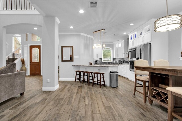 kitchen with white cabinets, light wood-type flooring, a breakfast bar, and a wealth of natural light