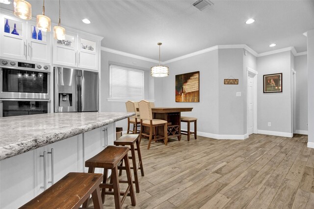 kitchen with light stone countertops, light hardwood / wood-style flooring, white cabinets, and appliances with stainless steel finishes