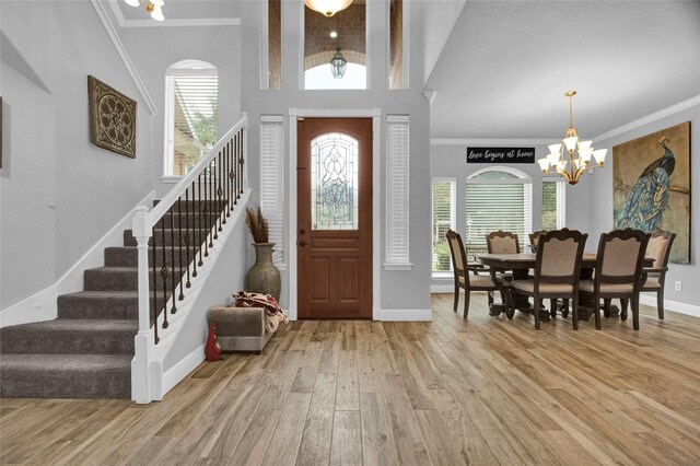 entrance foyer featuring vaulted ceiling with beams, a chandelier, crown molding, and wood-type flooring