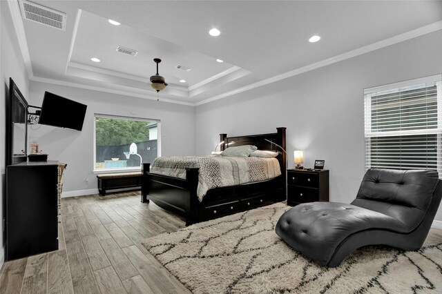 bedroom featuring a raised ceiling, light hardwood / wood-style flooring, ceiling fan, and ornamental molding