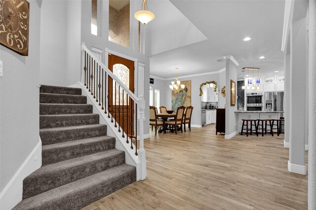 stairway featuring a chandelier, crown molding, and wood-type flooring