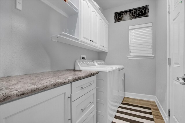 clothes washing area with separate washer and dryer, cabinets, and light wood-type flooring