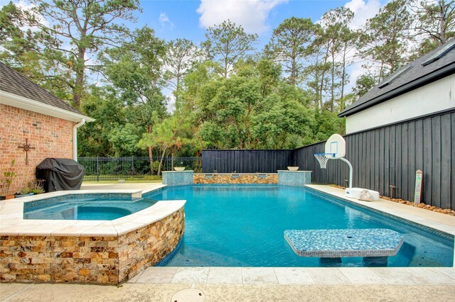 view of swimming pool with an in ground hot tub and a grill