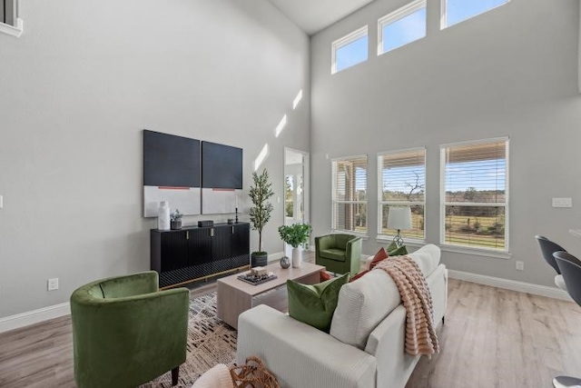 living room featuring a wealth of natural light, light hardwood / wood-style floors, and a high ceiling