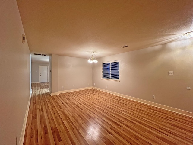 unfurnished room with wood-type flooring and a notable chandelier