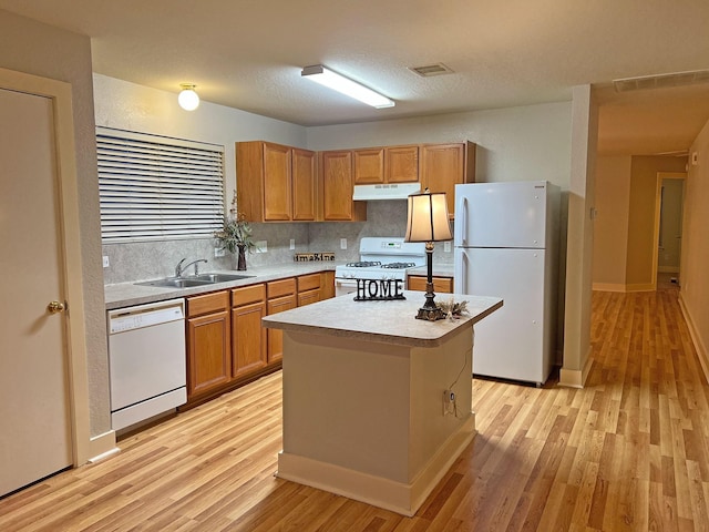 kitchen with a center island, white appliances, sink, decorative backsplash, and light hardwood / wood-style floors