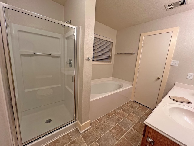 bathroom with plus walk in shower, tile patterned flooring, vanity, and a textured ceiling