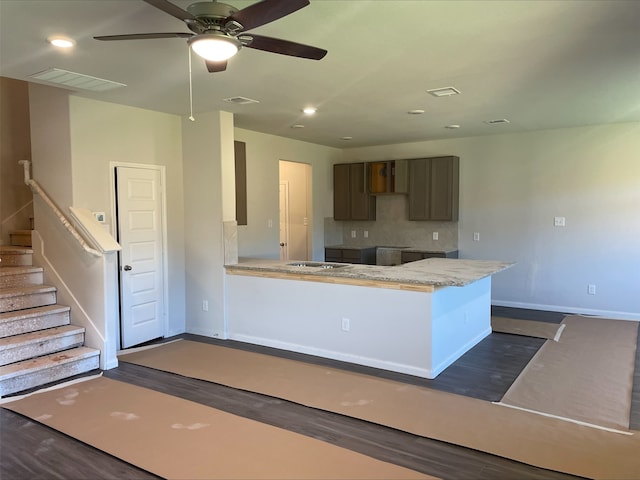 kitchen featuring backsplash, dark hardwood / wood-style floors, ceiling fan, light stone countertops, and kitchen peninsula