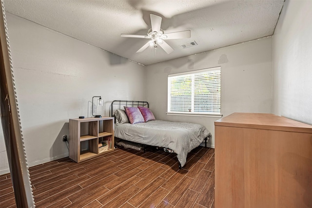 bedroom featuring a textured ceiling, ceiling fan, and dark wood-type flooring