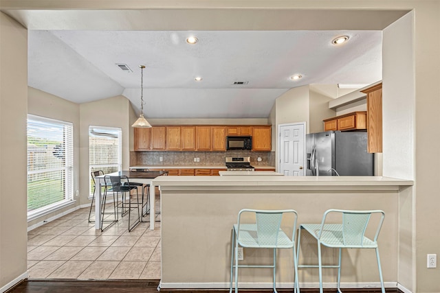 kitchen with kitchen peninsula, stainless steel appliances, lofted ceiling, and light hardwood / wood-style floors