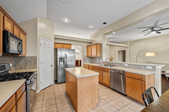 kitchen featuring appliances with stainless steel finishes, backsplash, ceiling fan, sink, and a kitchen island