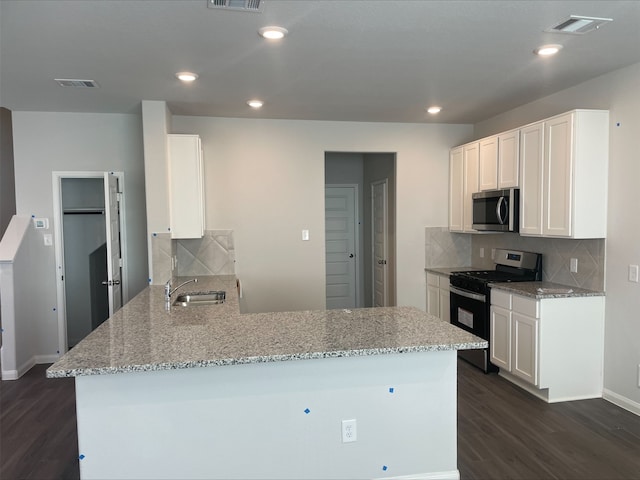 kitchen featuring kitchen peninsula, dark hardwood / wood-style flooring, white cabinets, and stainless steel appliances