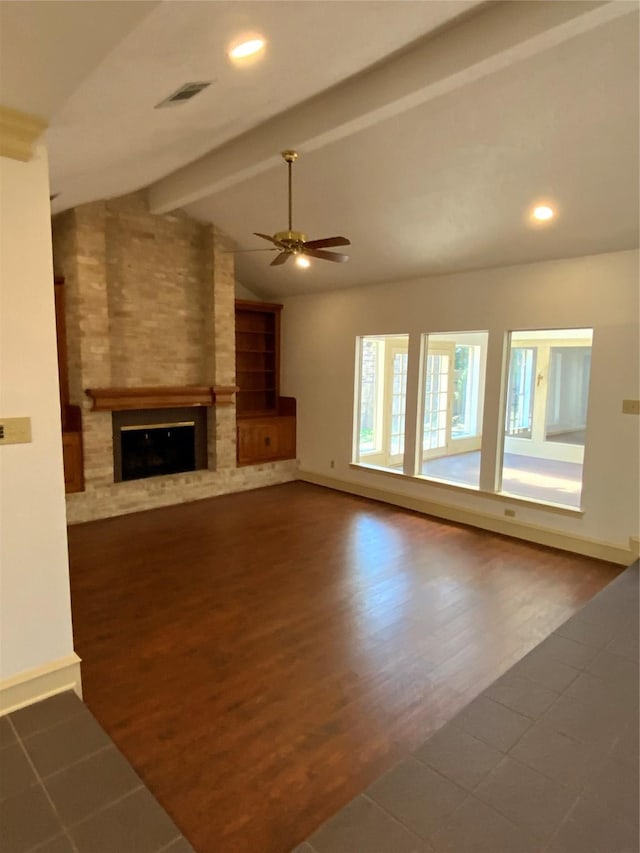 unfurnished living room featuring lofted ceiling with beams, a large fireplace, dark hardwood / wood-style flooring, and ceiling fan