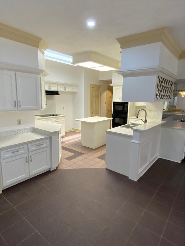 kitchen with black appliances, sink, kitchen peninsula, ornamental molding, and white cabinetry