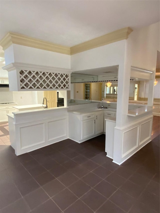 kitchen featuring kitchen peninsula, backsplash, white cabinets, and sink