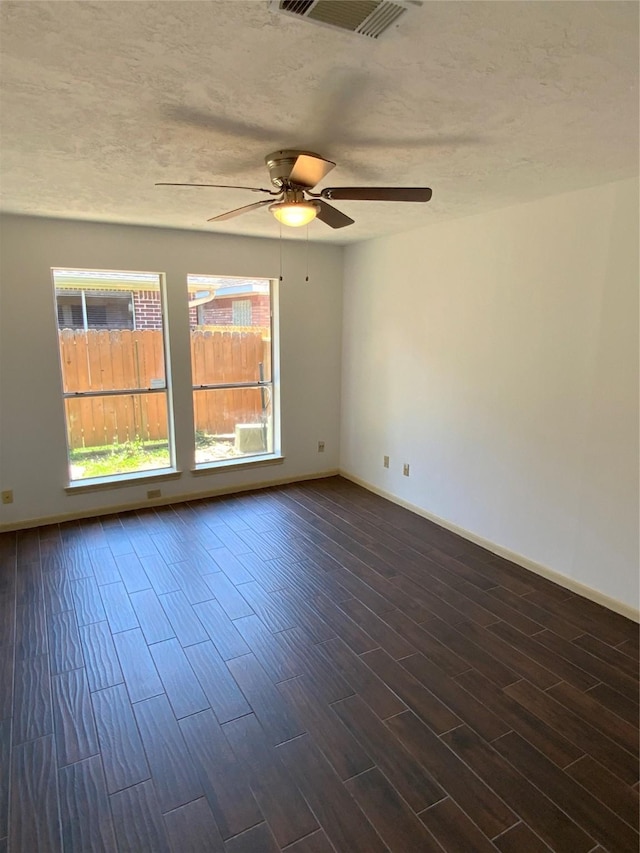 empty room featuring a textured ceiling, ceiling fan, and dark wood-type flooring