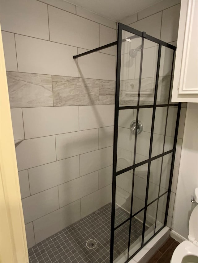 bathroom with a tile shower and toilet