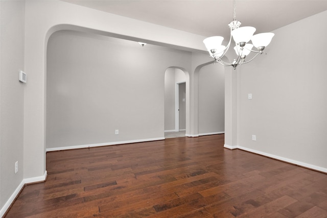 unfurnished room with a notable chandelier and dark hardwood / wood-style flooring