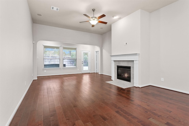 unfurnished living room with a fireplace, ceiling fan, and dark wood-type flooring