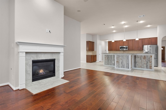 unfurnished living room featuring a premium fireplace and light hardwood / wood-style floors