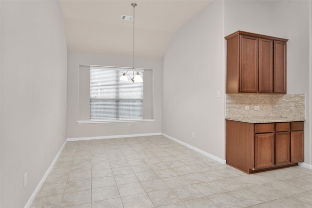 kitchen featuring hanging light fixtures, a notable chandelier, vaulted ceiling, decorative backsplash, and light tile patterned flooring