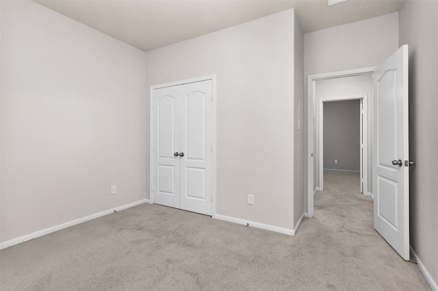 unfurnished bedroom with light colored carpet and a closet