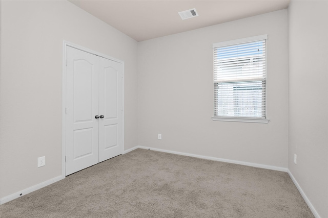 unfurnished bedroom featuring light colored carpet and a closet