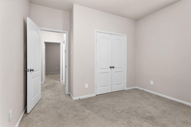 unfurnished bedroom featuring light carpet and a closet