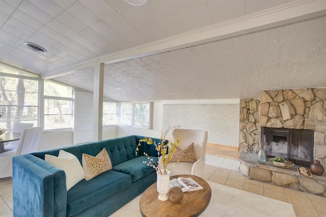 living room featuring light tile patterned flooring, a stone fireplace, a textured ceiling, and vaulted ceiling