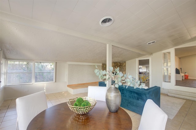 tiled dining space with a textured ceiling and lofted ceiling