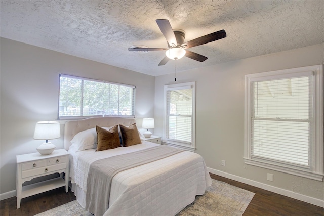 bedroom with a textured ceiling, ceiling fan, and dark hardwood / wood-style floors