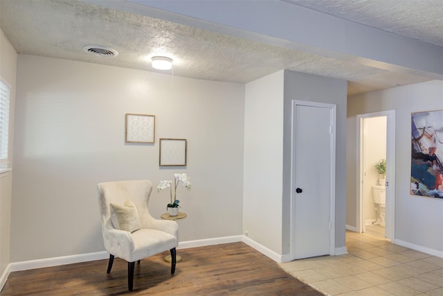 living area featuring a textured ceiling and light hardwood / wood-style flooring