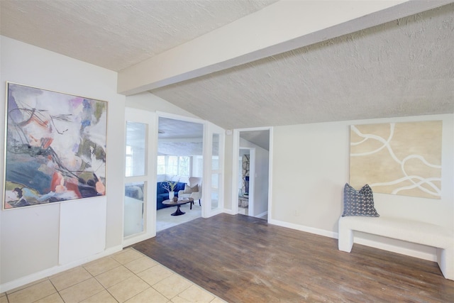 interior space featuring a textured ceiling, lofted ceiling with beams, and hardwood / wood-style flooring