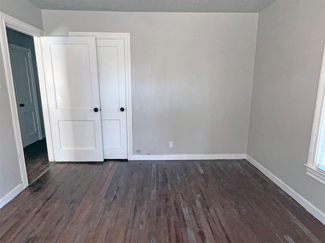 unfurnished bedroom featuring a closet and dark wood-type flooring