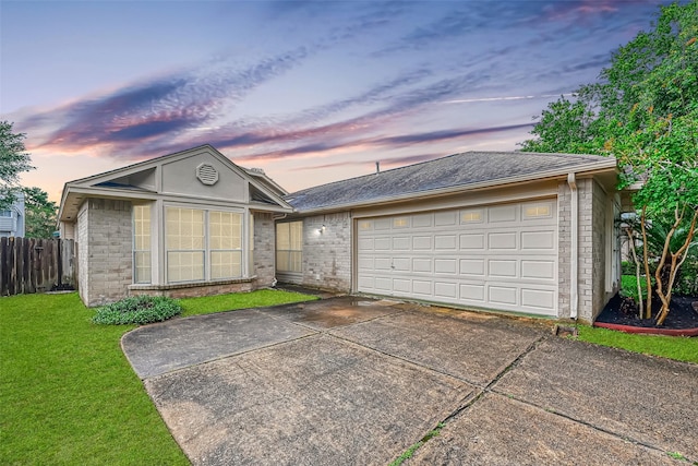 ranch-style home with a garage, brick siding, fence, driveway, and a lawn