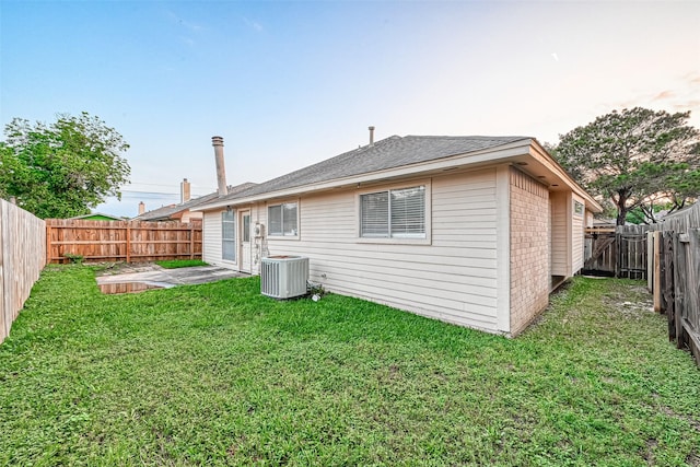 back of property featuring a yard, brick siding, a fenced backyard, and cooling unit