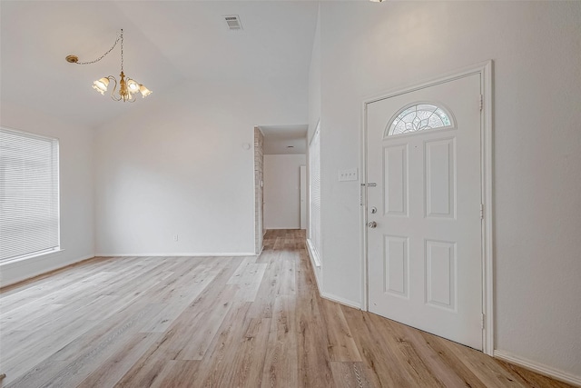 foyer entrance featuring a chandelier, high vaulted ceiling, visible vents, baseboards, and light wood-style floors