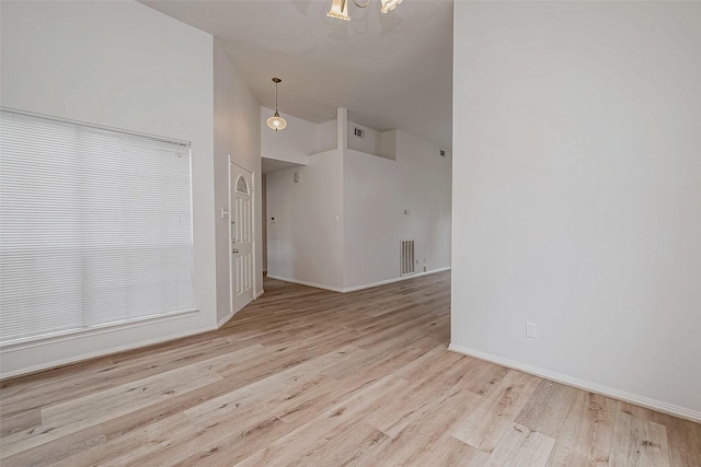 unfurnished room featuring light wood-style floors, lofted ceiling, visible vents, and baseboards