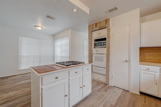 kitchen with stainless steel appliances, light countertops, visible vents, light wood-style floors, and white cabinetry