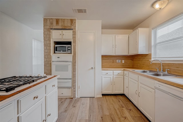 kitchen with stainless steel appliances, a sink, visible vents, white cabinets, and light countertops