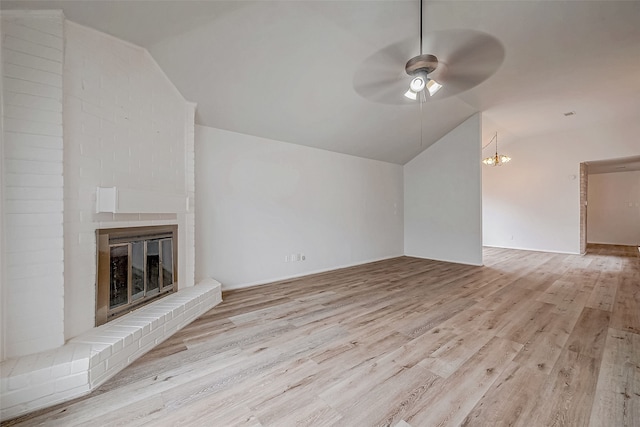 unfurnished living room with a brick fireplace, ceiling fan, vaulted ceiling, and light wood finished floors