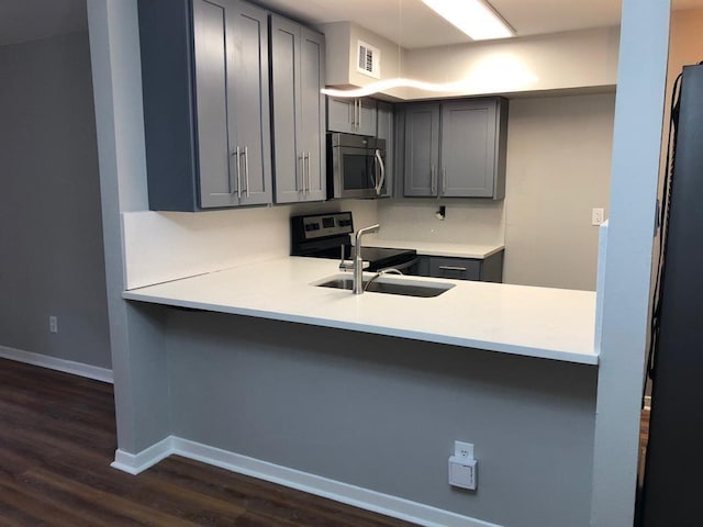 kitchen with kitchen peninsula, electric range, gray cabinets, and sink