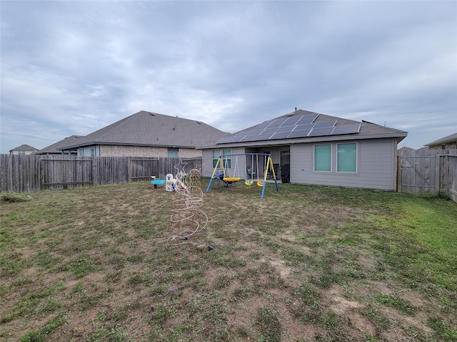 rear view of property featuring solar panels, a playground, and a lawn