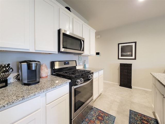 kitchen featuring white cabinets, light tile patterned floors, stainless steel appliances, and light stone countertops