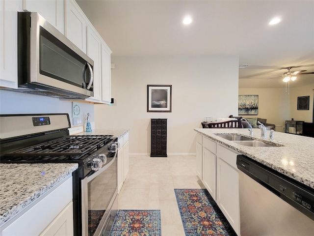 kitchen featuring light stone countertops, stainless steel appliances, sink, light tile patterned floors, and white cabinetry