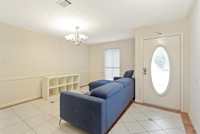 tiled entrance foyer with ornamental molding, a textured ceiling, and a notable chandelier